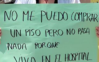 Médica MIR en protesta sostiene un cartel que denuncia que no puede comprarse un piso porque vive en el hospital