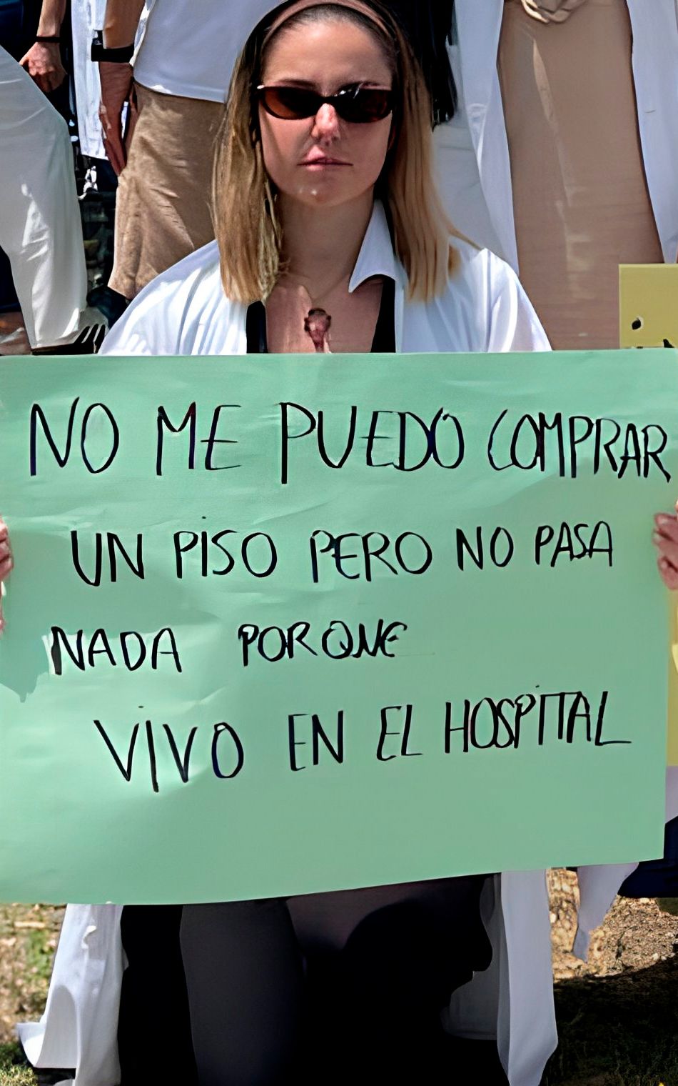 Médica MIR en protesta sostiene un cartel que denuncia que no puede comprarse un piso porque vive en el hospital