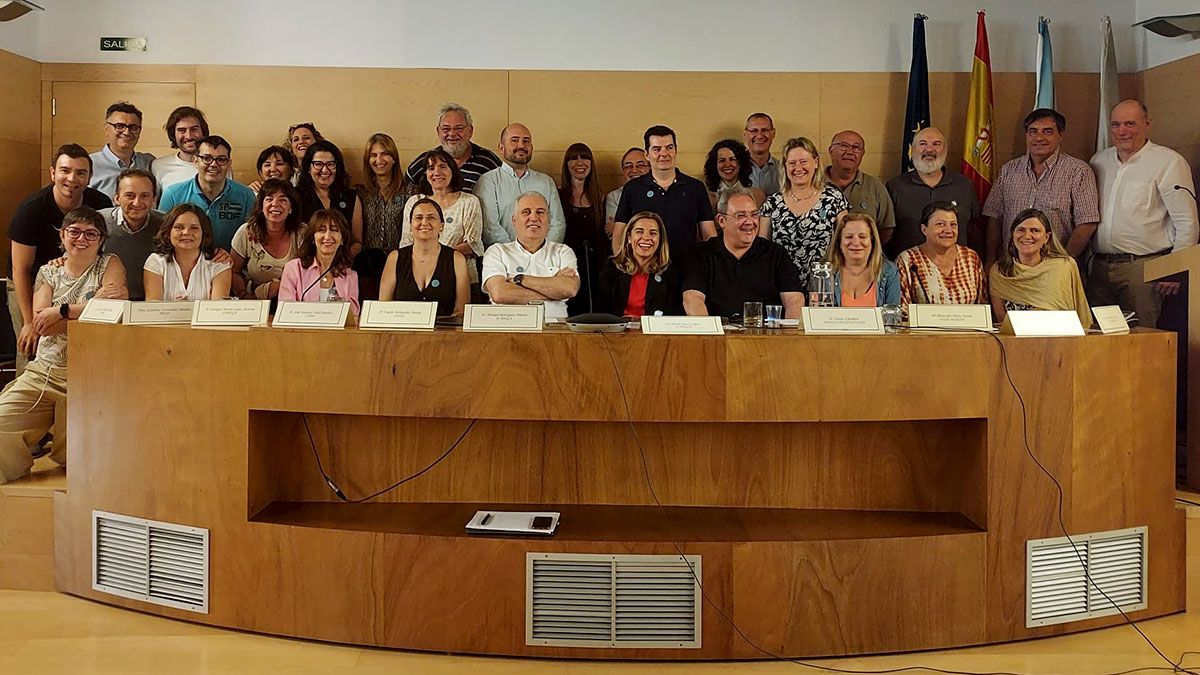 Unidad y compromiso en la defensa del Estatuto Médico Foto de grupo de los asistentes y ponentes del seminario en Vigo, con miembros de APEMYF y Sindicato Médico Avanza sonriendo frente a la mesa del evento, junto a las banderas institucionales.