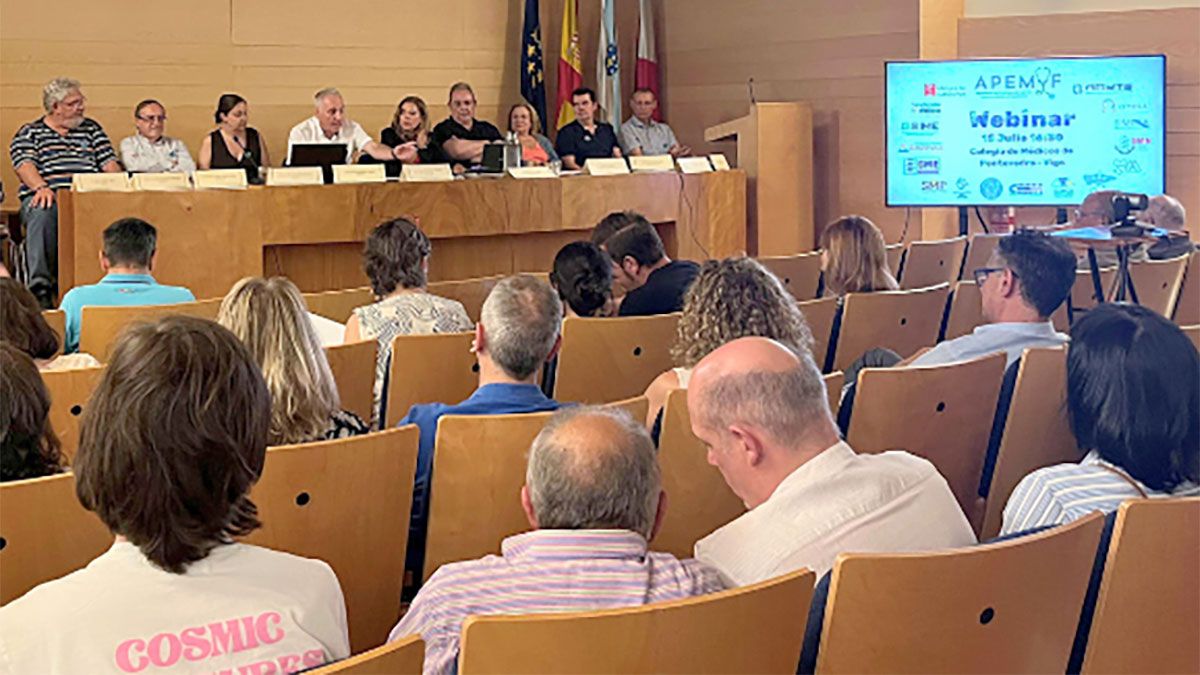 Representantes de APEMYF y Sindicato Médico Avanza, sentados en la mesa principal de un seminario en Vigo, con público asistente y una pantalla que anuncia la jornada dedicada a la defensa del Estatuto Médico.