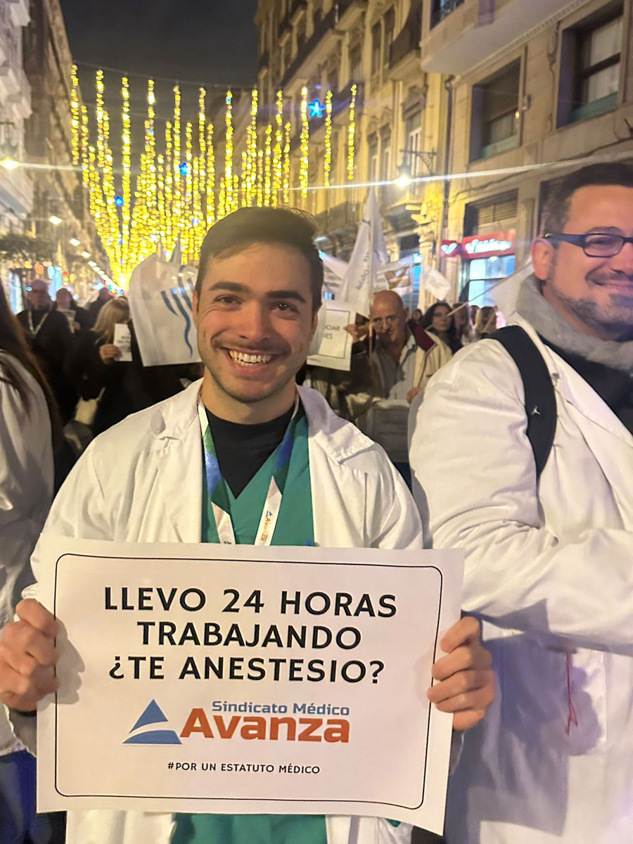 Médico con bata muestra un cartel “Llevo 24 horas trabajando ¿te anestesio?” en una manifestación.
